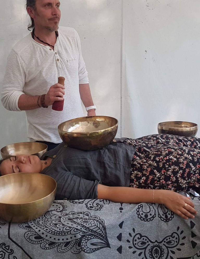 Soin vibratoire au bol tibétain – relaxation profonde Soin énergétique aux bols chantants posé sur le corps d’une femme allongée, guidé par un praticien, favorisant détente, harmonisation et apa